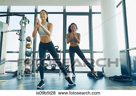 Two young women exercising in gym, doing aerobic workout View Large Photo Image Stock Photo - Two young women exercising in gym, doing aerobic workout. Fotosearch