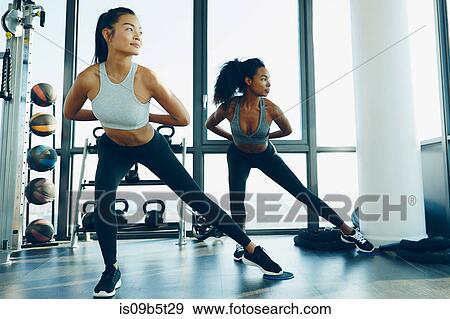 Stock Photo - Two young women exercising in gym, doing aerobic workout. Fotosearch