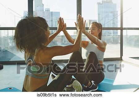 Stock Photograph - Two young women exercising in gym, doing sit-ups. Fotosearch