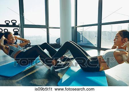 Two young women exercising in gym, doing sit-ups View Large Photo Image Stock Photograph - Two young women exercising in gym, doing sit-ups. Fotosearch