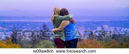 Two young women, standing on hillside, hugging, looking at view, rear view View Large Photo Image Stock Image - Two young women, standing on hillside, hugging, looking at view, rear view. Fotosearch