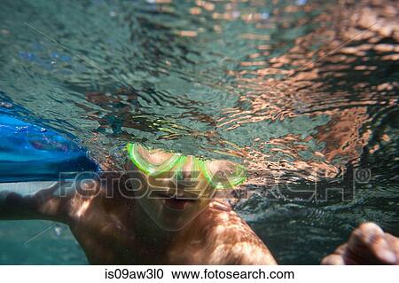 Underwater view of boy wearing goggles swimming underwater View Large Photo Image Stock Image - Underwater view of boy wearing goggles swimming underwater. Fotosearch