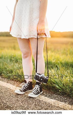 Waist down of woman holding camera on roadside View Large Photo Image Stock Image - Waist down of woman holding camera on roadside. Fotosearch