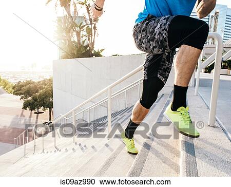 Stock Image - Waist down view of man training, running up stairway at sport facility, downtown San Diego, California, USA. Fotosearch