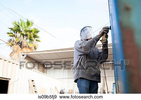 Stock Photo - Welder using power tool on shipping container. Fotosearch