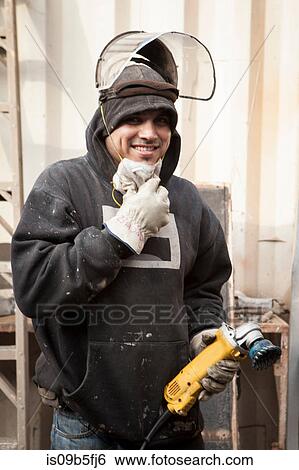 Welder wearing safety equipment holding power tool smiling View Large Photo Image Stock Photograph - Welder wearing safety equipment holding power tool smiling. Fotosearch