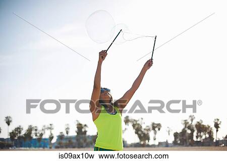 Woman, arms raised using bubbles wands to make bubbles View Large Photo Image Stock Photo - Woman, arms raised using bubbles wands to make bubbles. Fotosearch
