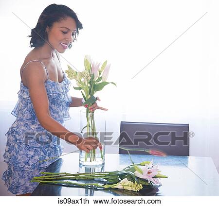 Woman arranging flowers in vase on table View Large Photo Image Stock Image - Woman arranging flowers in vase on table. Fotosearch