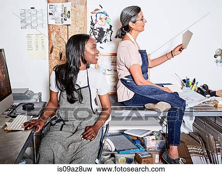 Woman at desk wearing aprons looking at colour swatch View Large Photo Image Stock Photo - Woman at desk wearing aprons looking at colour swatch. Fotosearch