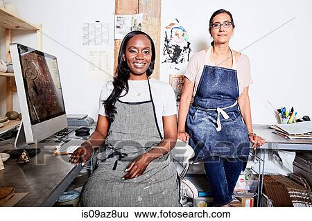 Woman at desk wearing aprons looking at camera smiling View Large Photo Image Stock Photograph - Woman at desk wearing aprons looking at camera smiling. Fotosearch