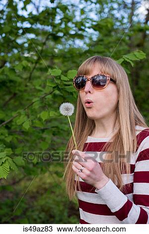 Stock Image - Woman blowing dandelion. Fotosearch