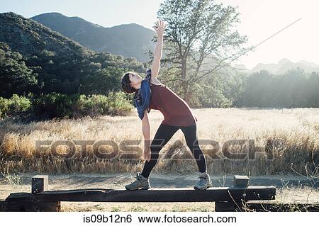 Stock Photograph - Woman by mountains doing stretching exercises, Malibu, California, USA. Fotosearch