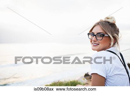 Woman by ocean looking over shoulder at camera smiling, Encinitas, California, USA View Large Photo Image Stock Photo - Woman by ocean looking over shoulder at camera smiling, Encinitas, California, USA. Fotosearch