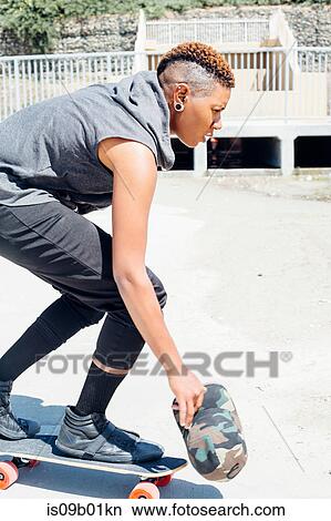 Woman crouching on skateboard View Large Photo Image Picture - Woman crouching on skateboard. Fotosearch