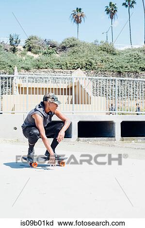 Woman crouching on skateboard View Large Photo Image Stock Image - Woman crouching on skateboard. Fotosearch