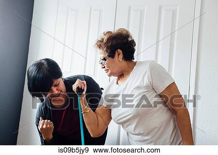 Woman helping senior woman to use resistance band View Large Photo Image Stock Photo - Woman helping senior woman to use resistance band. Fotosearch