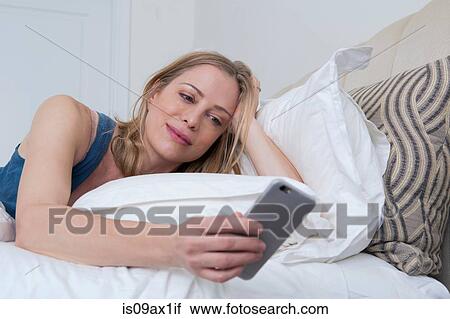 Woman in bed reading smartphone texts View Large Photo Image Stock Image - Woman in bed reading smartphone texts. Fotosearch