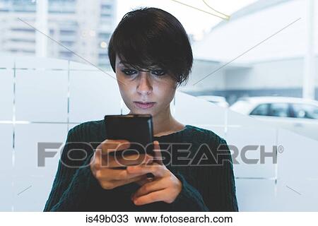 Stock Image - Woman in cafe looking at smartphone. Fotosearch