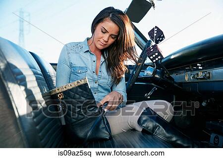 Stock Photography - Woman in convertible car looking in handbag, Los Angeles, California, USA. Fotosearch