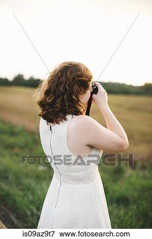 Woman in field taking photograph View Large Photo Image Stock Photo - Woman in field taking photograph. Fotosearch