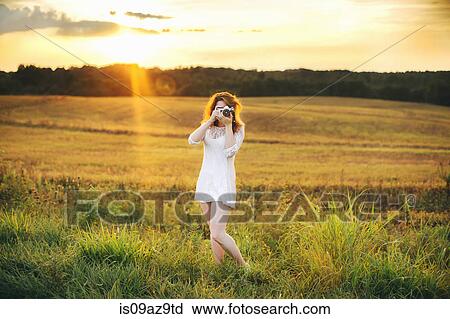 Woman in field taking photograph using camera View Large Photo Image Stock Image - Woman in field taking photograph using camera. Fotosearch