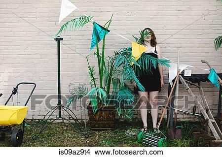 Woman in garden camouflaged by pot plant View Large Photo Image Picture - Woman in garden camouflaged by pot plant. Fotosearch
