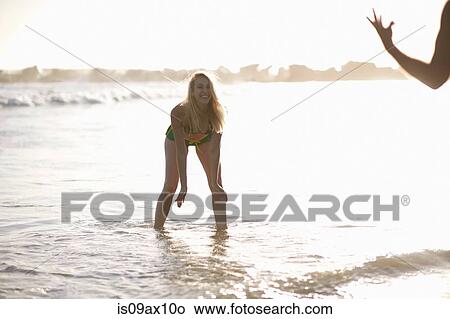 Woman in ocean bending forwards laughing View Large Photo Image Picture - Woman in ocean bending forwards laughing. Fotosearch