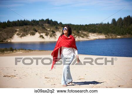 Stock Image - Woman in red shawl enjoying beach. Fotosearch