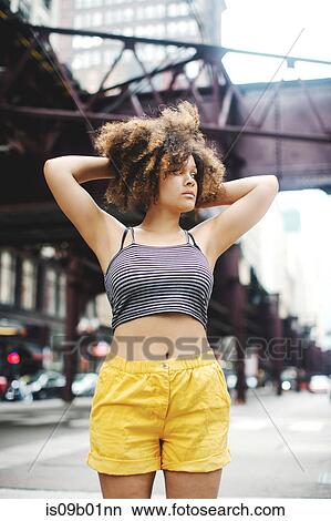 Woman in street, hands behind head looking away, Chicago, Illinois View Large Photo Image Picture - Woman in street, hands behind head looking away, Chicago, Illinois. Fotosearch