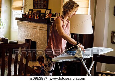 Woman ironing whilst toddler daughter playing on floor View Large Photo Image Stock Photo - Woman ironing whilst toddler daughter playing on floor. Fotosearch