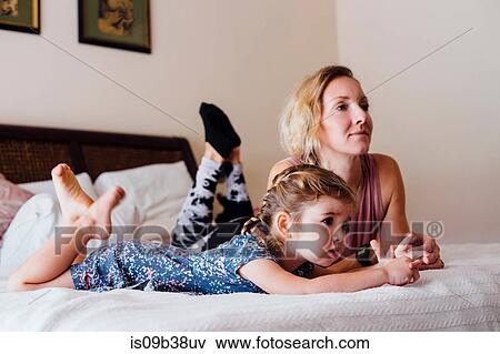 Woman lying on bed with toddler daughter watching TV View Large Photo Image Stock Photo - Woman lying on bed with toddler daughter watching TV. Fotosearch