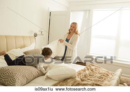 Woman making bed whilst toddler son playing View Large Photo Image Stock Photograph - Woman making bed whilst toddler son playing. Fotosearch