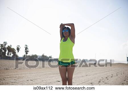 Woman on beach wearing sunglasses arms raised stretching View Large Photo Image Stock Image - Woman on beach wearing sunglasses arms raised stretching. Fotosearch
