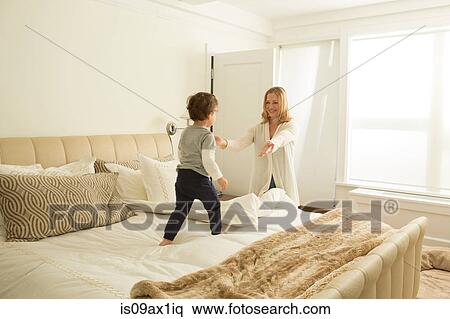 Woman opening arms to toddler son on bed View Large Photo Image Stock Photography - Woman opening arms to toddler son on bed. Fotosearch