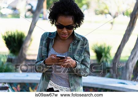 Woman outdoors, looking at smartphone View Large Photo Image Stock Photo - Woman outdoors, looking at smartphone. Fotosearch
