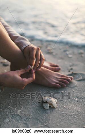 Stock Image - Woman playing with seashells on beach. Fotosearch