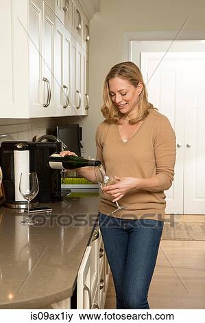 Woman pouring white wine into glass in kitchen View Large Photo Image Stock Photo - Woman pouring white wine into glass in kitchen. Fotosearch