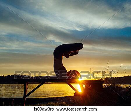 Woman practising yoga by lake at sunset View Large Photo Image Picture - Woman practising yoga by lake at sunset. Fotosearch