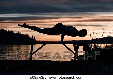 Woman practising yoga by lake at sunset View Large Photo Image Stock Photo - Woman practising yoga by lake at sunset. Fotosearch