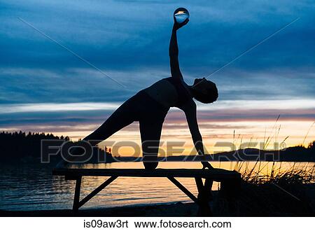 Woman practising yoga by lake at sunset View Large Photo Image Stock Photograph - Woman practising yoga by lake at sunset. Fotosearch