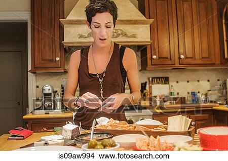 Picture - Woman preparing snacks at kitchen counter. Fotosearch