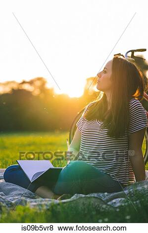 Stock Photo - Woman reading book on grass. Fotosearch