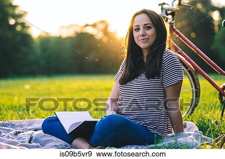 Stock Photo - Woman reading book on grass. Fotosearch