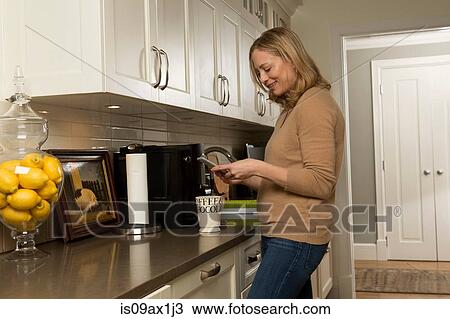 Woman reading smartphone text in kitchen View Large Photo Image Stock Image - Woman reading smartphone text in kitchen. Fotosearch