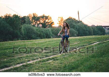 Woman riding bicycle on grass View Large Photo Image Stock Image - Woman riding bicycle on grass. Fotosearch