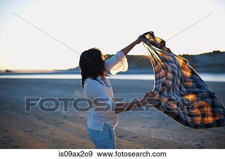 Woman shaking blanket on beach at sunset, Cannon Beach, California, USA View Large Photo Image Stock Photo - Woman shaking blanket on beach at sunset, Cannon Beach, California, USA. Fotosearch