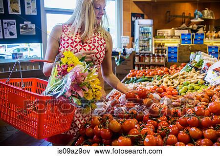 Stock Photo - Woman shopping for vegetables in supermarket. Fotosearch
