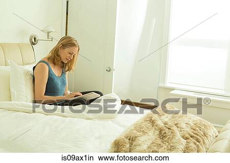 Woman sitting on bed using touchscreen on digital tablet View Large Photo Image Picture - Woman sitting on bed using touchscreen on digital tablet. Fotosearch