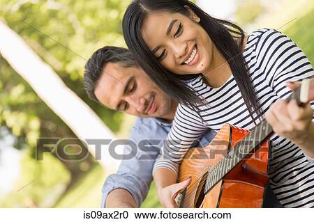 Woman sitting on grass playing acoustic guitar smiling View Large Photo Image Stock Image - Woman sitting on grass playing acoustic guitar smiling. Fotosearch