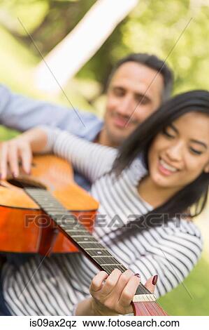 Woman sitting on grass playing acoustic guitar smiling View Large Photo Image Stock Photo - Woman sitting on grass playing acoustic guitar smiling. Fotosearch